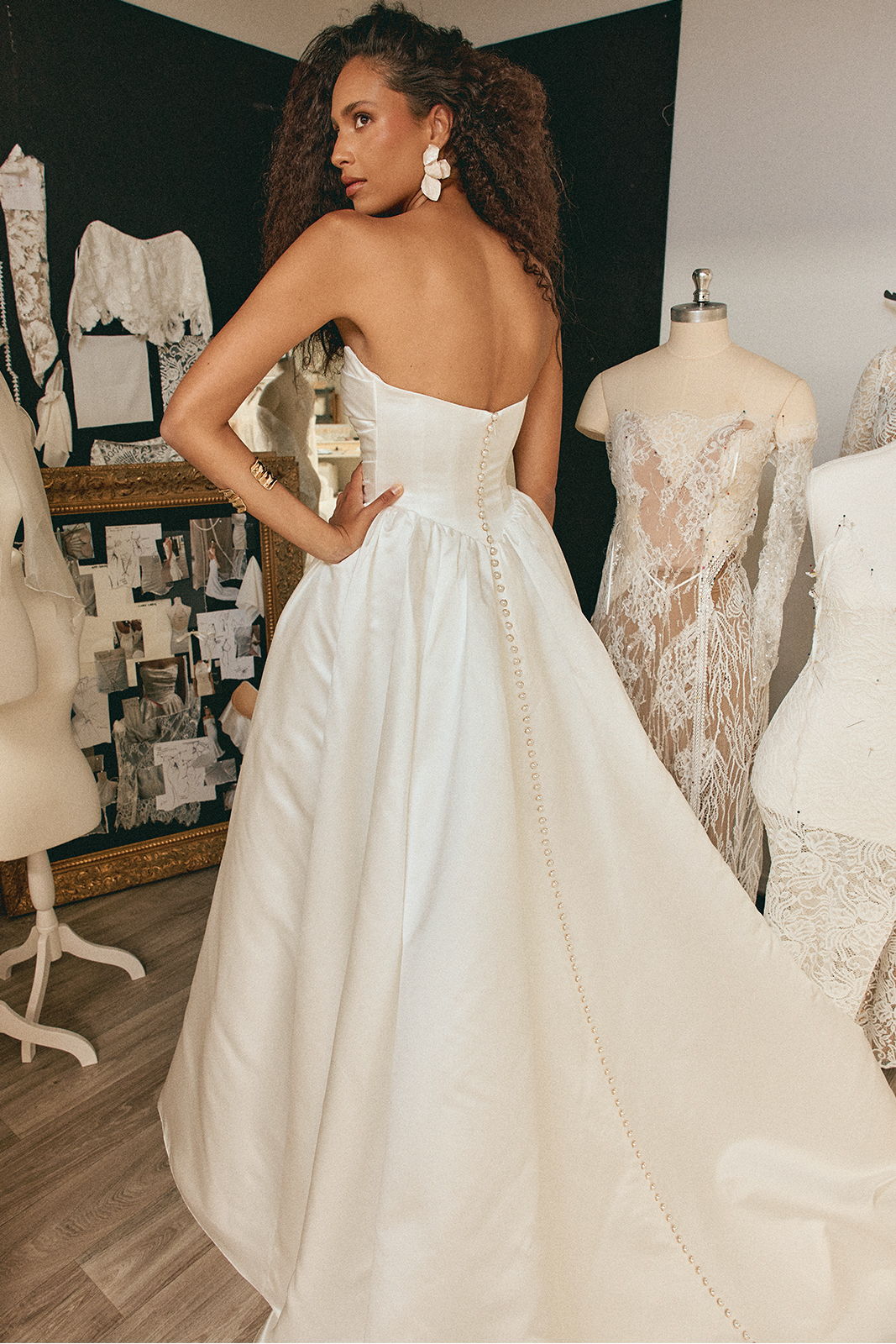 Model wearing a strapless white gown, showcasing a dramatic back view in a studio.