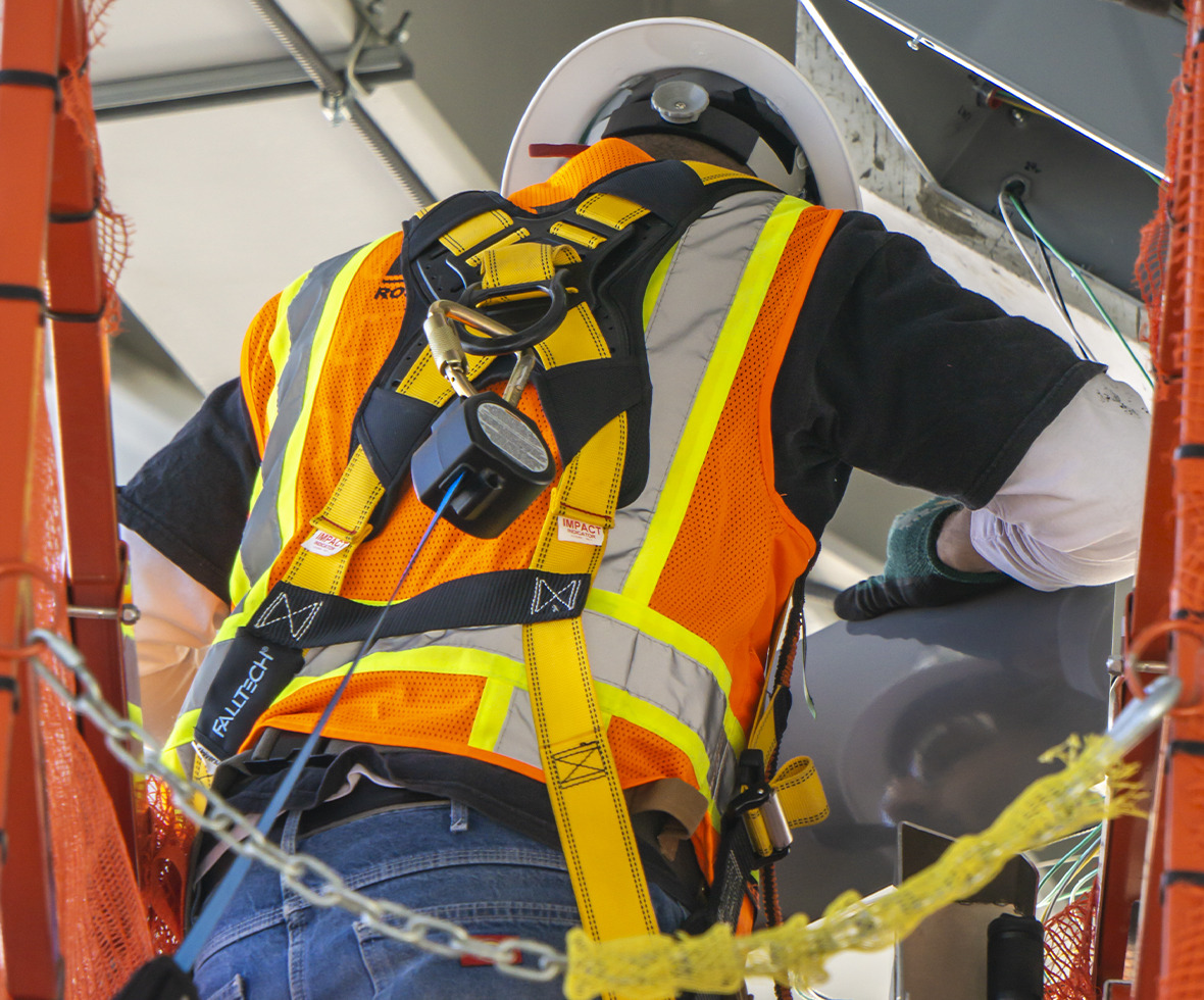 Construction worker climbing onto scissor lift wearing a Journeyman Flex Aluminum harness and self-retracting lifeline