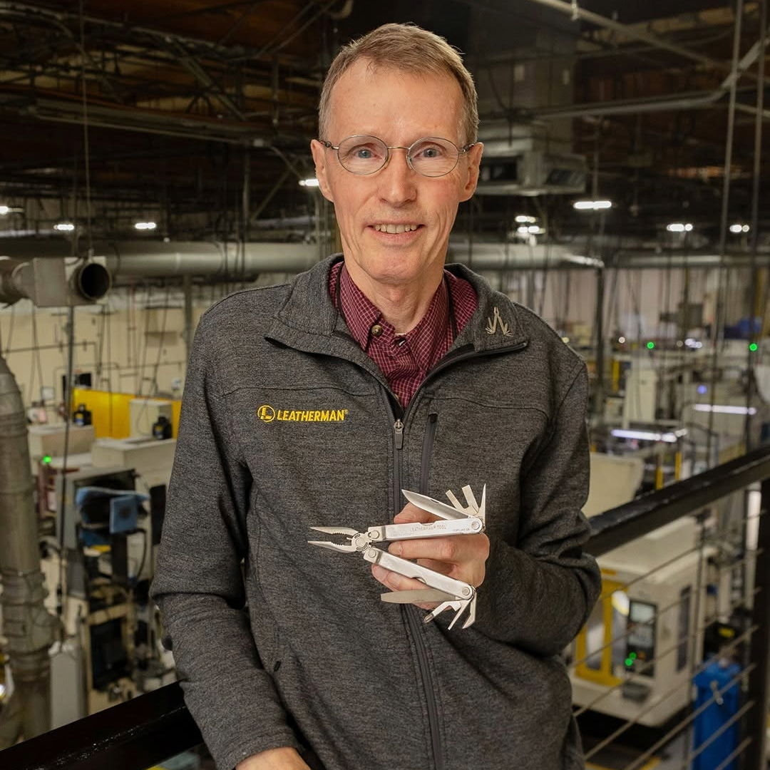 Person holding a model or tool in a workshop or industrial setting.