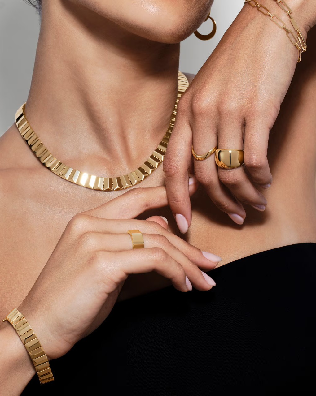 Woman wearing gold jewelry, including necklace, rings, and bracelets.