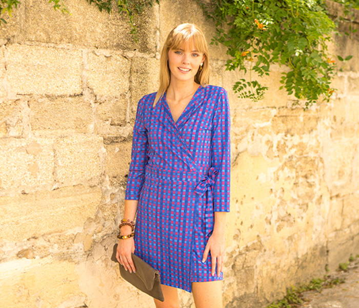 Woman wearing Bar Harbor Gingham Wrap Dress in front of brick wall.