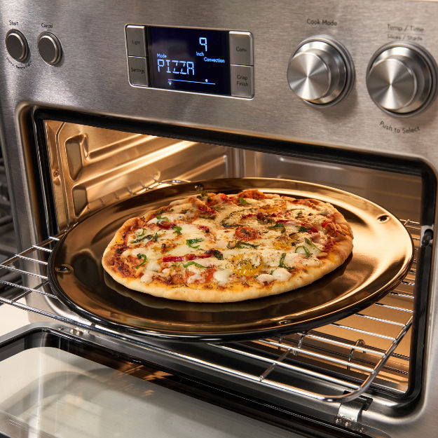 A pizza on a baking tray in an oven.