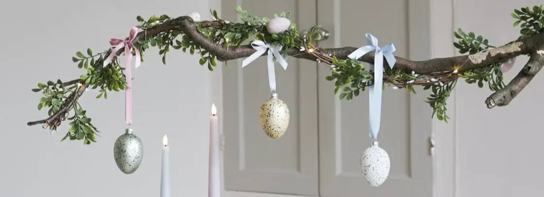 Completed hanging branch Easter table decorationand garland hanging above a dining setup
