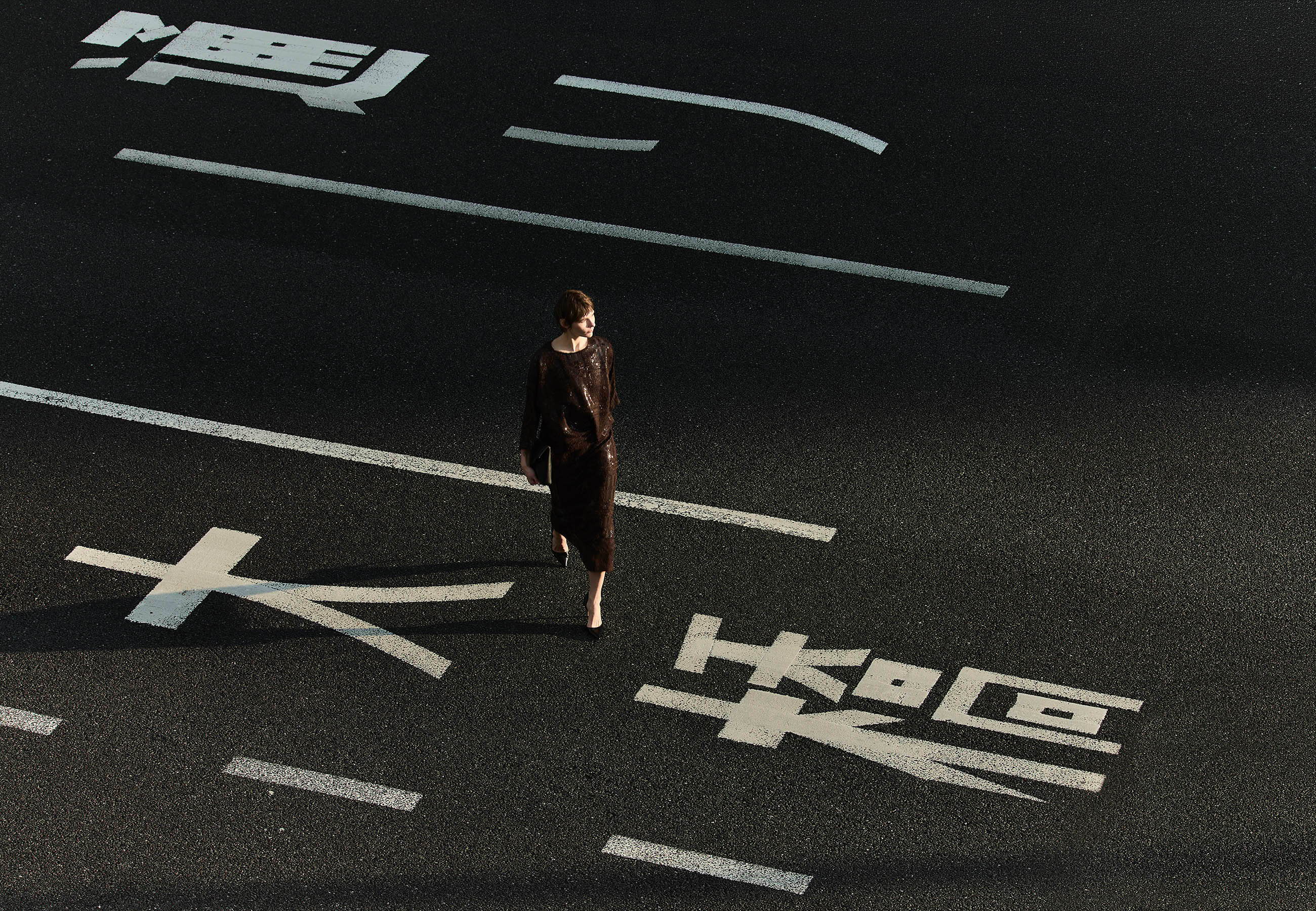 A person walking on a road with painted markings.