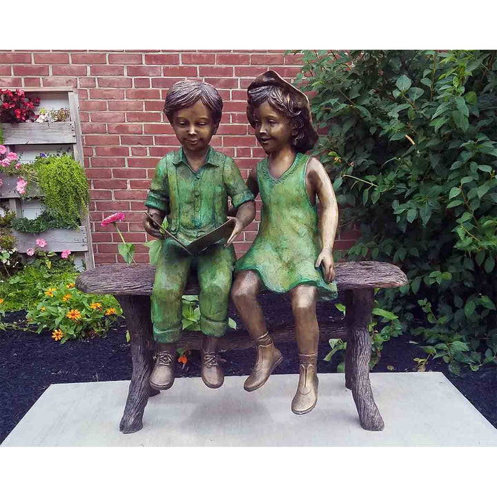 bronze statue of a boy and girl reading a book on a bench - Randolph Rose Collection