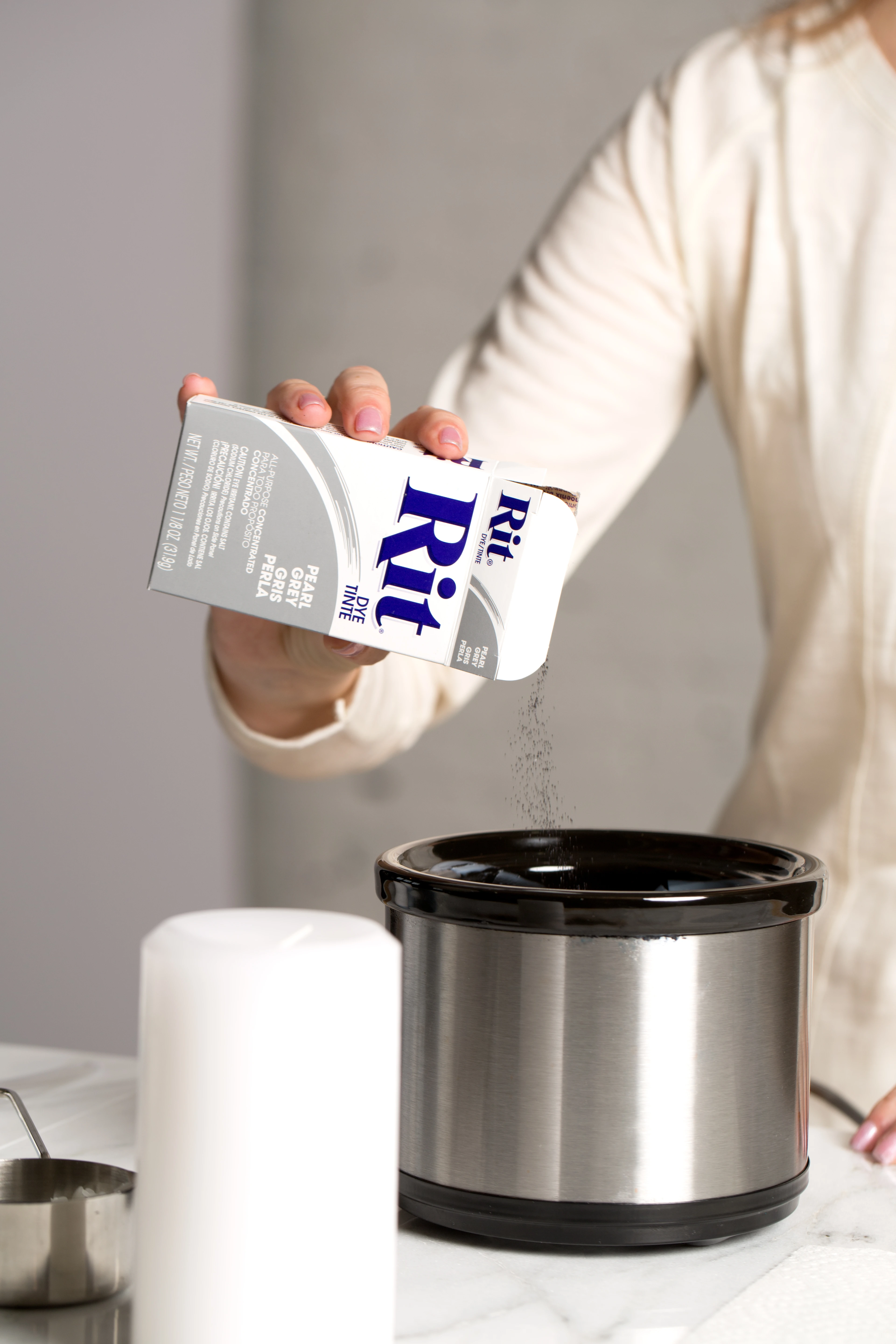 Person pouring Rit dye into a black container on a countertop.