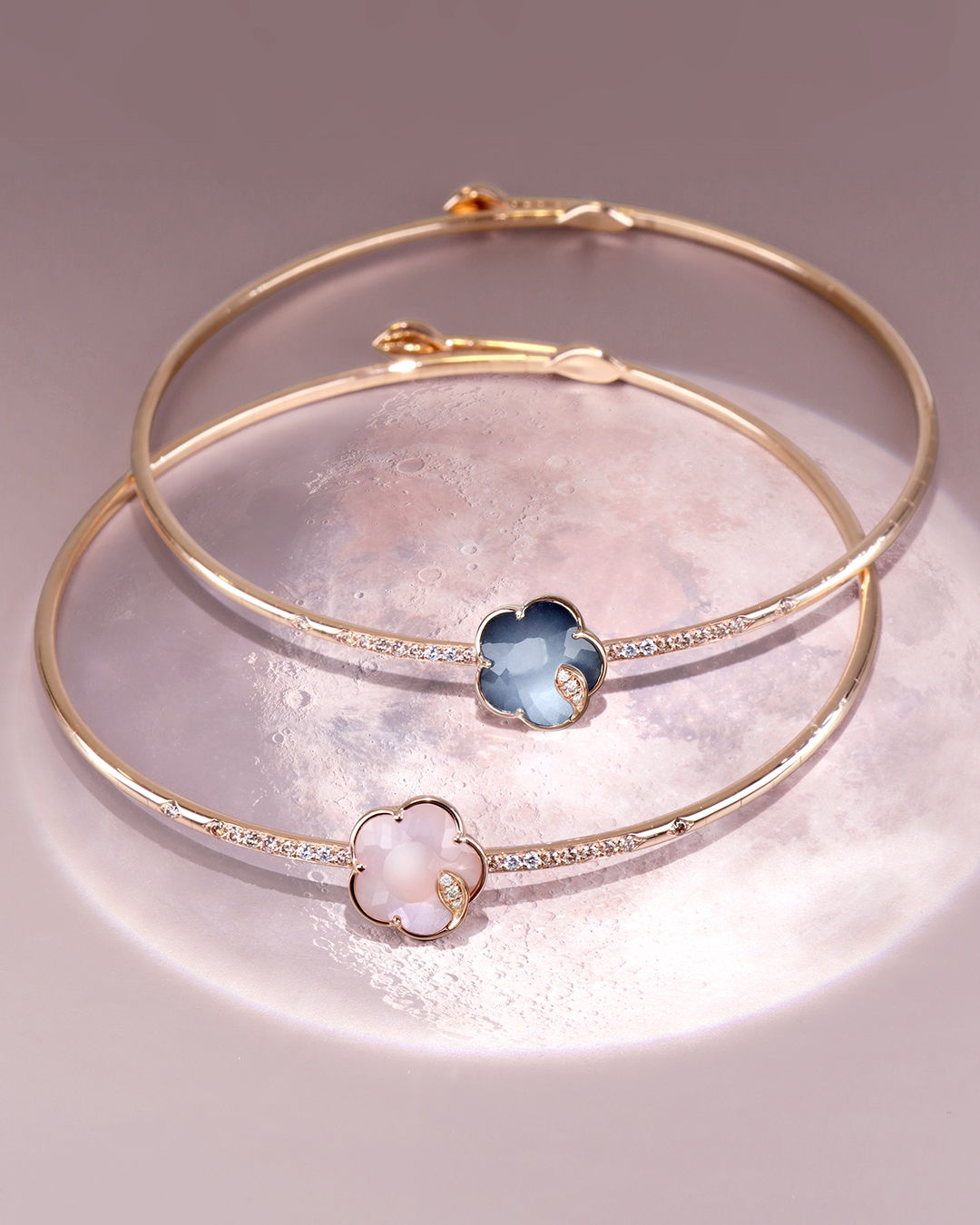 Two gold bangles with floral designs featuring colorful stones.