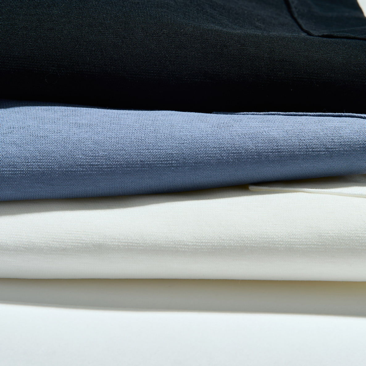 Stack of folded fabrics in black, blue, and white colors.