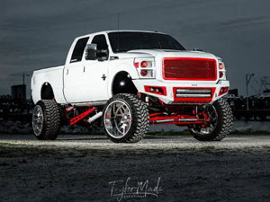 Corbin's lifted white 2016 Ford F250 Super Duty with red grille and custom bumper photographed at night