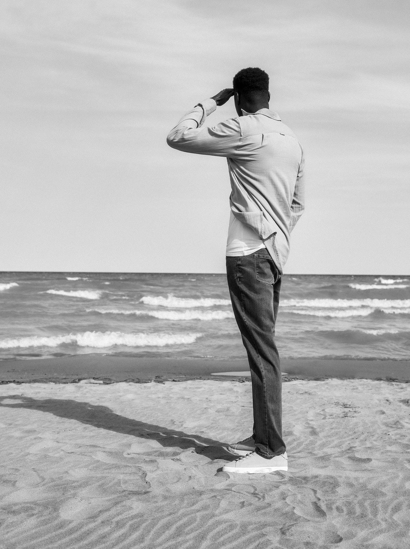 Tall man looking at the water wearing a linen shirt and dark wash jeans