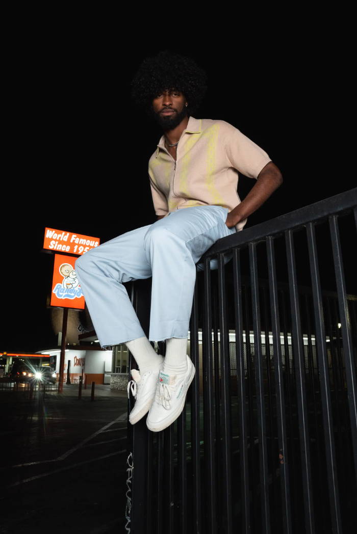 male model in reeboks sitting on a fence