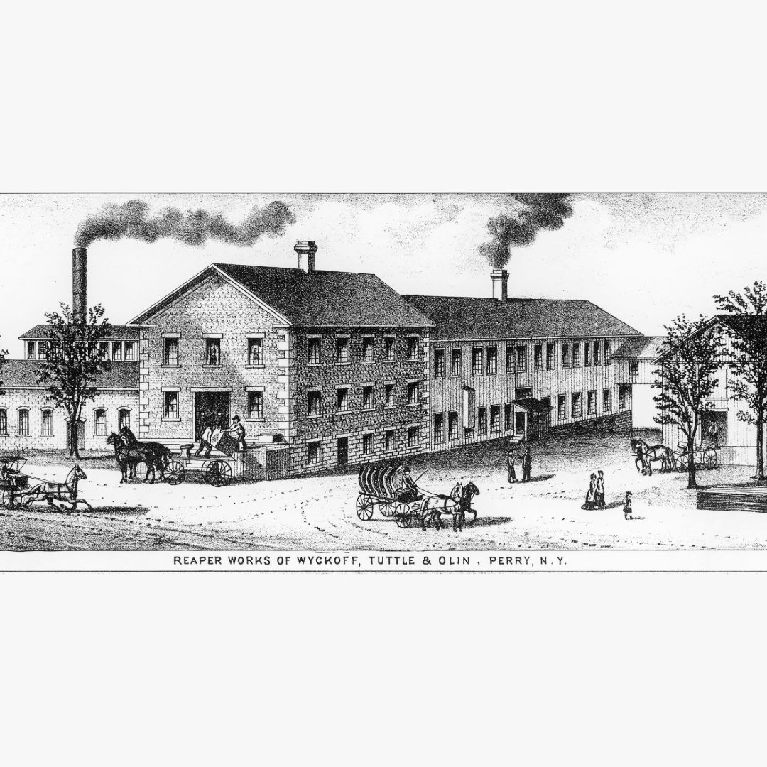 Historic building with smokestacks, horses, and people in a busy setting.