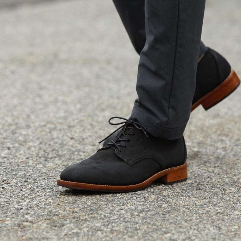 A man walking in a pair of Adelante black leather wide width derby dress shoes with a stacked brown leather sole.