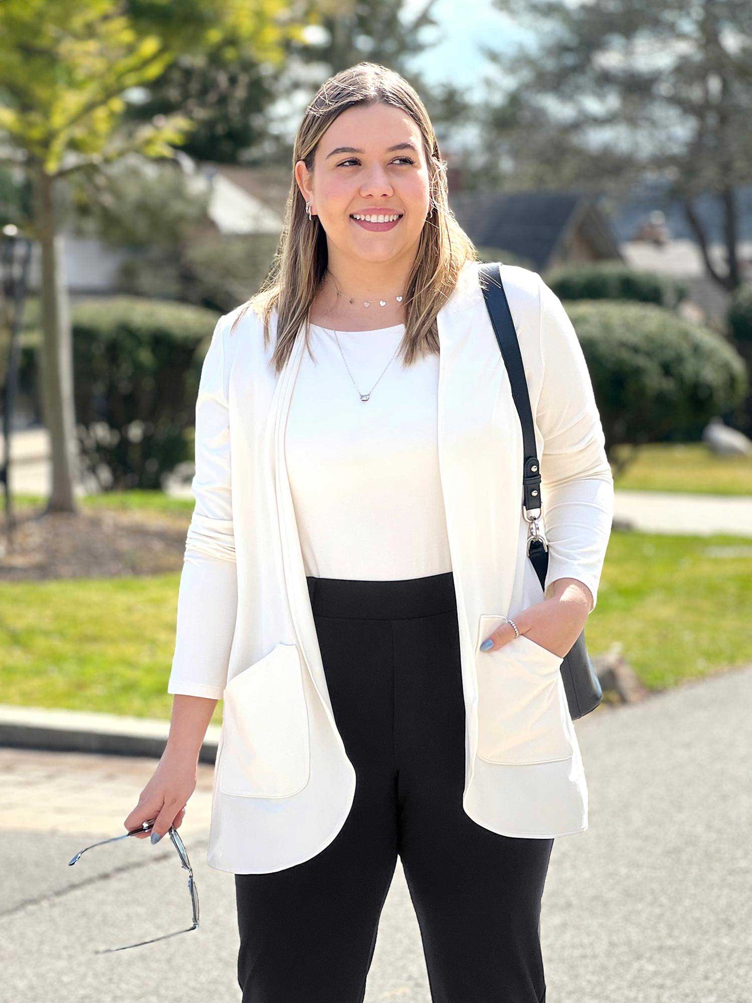 Woman standing wearing Miik's Sade open-front pocket cardigan in white over a matching with black pants