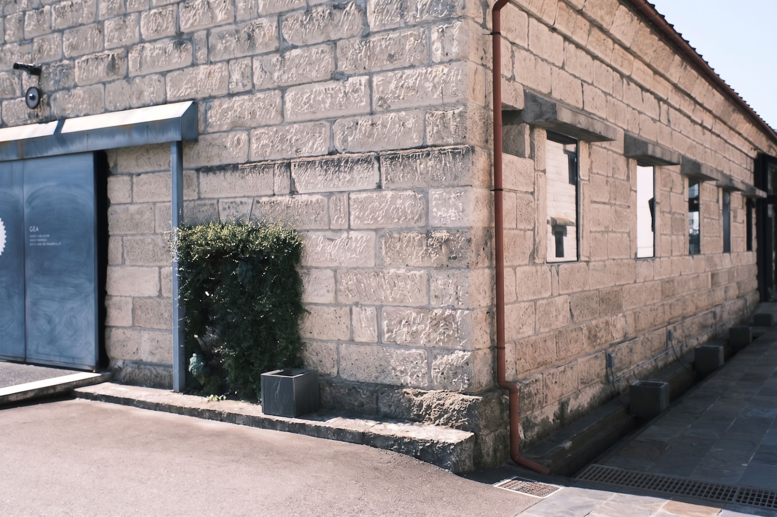 Stone building corner with gray door and several windows.