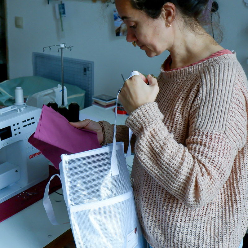 women getting fabric out of a white project bag in a sewing room