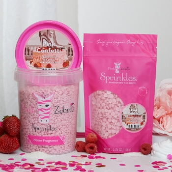 Two pink baking products next to strawberries and rose petals.