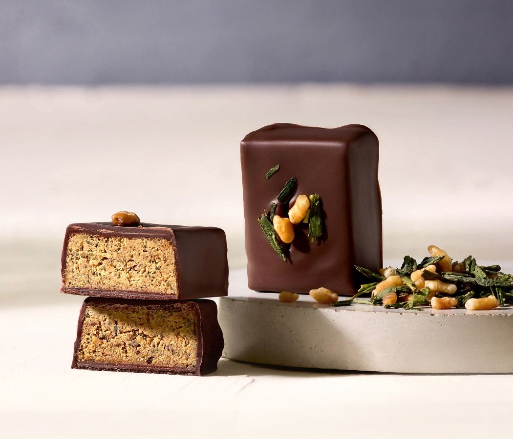 Chocolate-covered snack bars with nuts on a white plate.