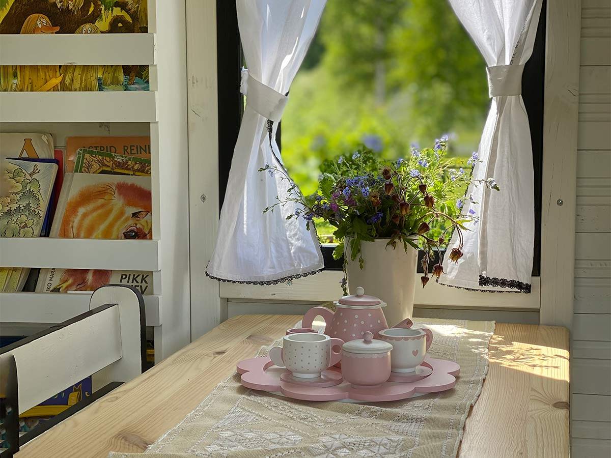 Inside view with kids furniture and curtains of Custom Wooden Playhouse by WholeWoodPlayhouses 