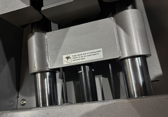 Close-up of machinery components with a warning label.