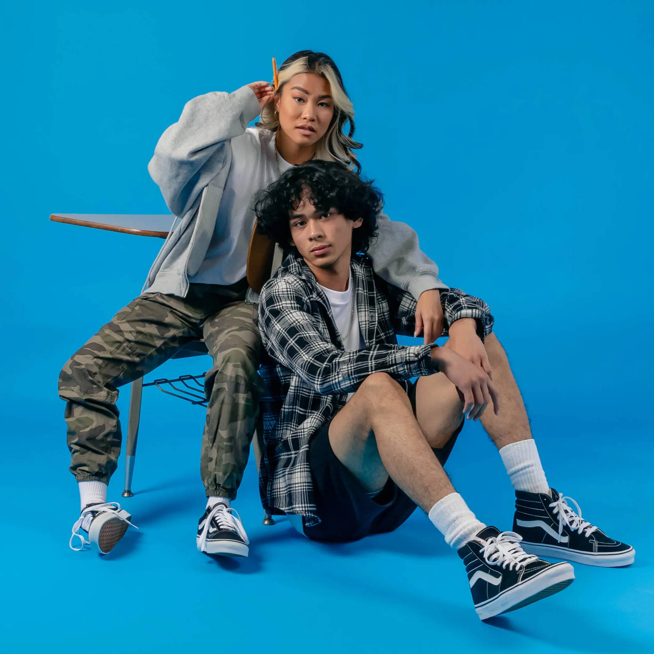 young male and female model by school desk wearing black vans