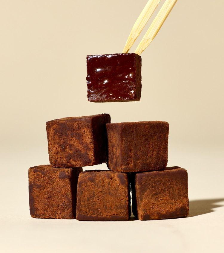 Chocolate cubes stacked with one being lifted by chopsticks.