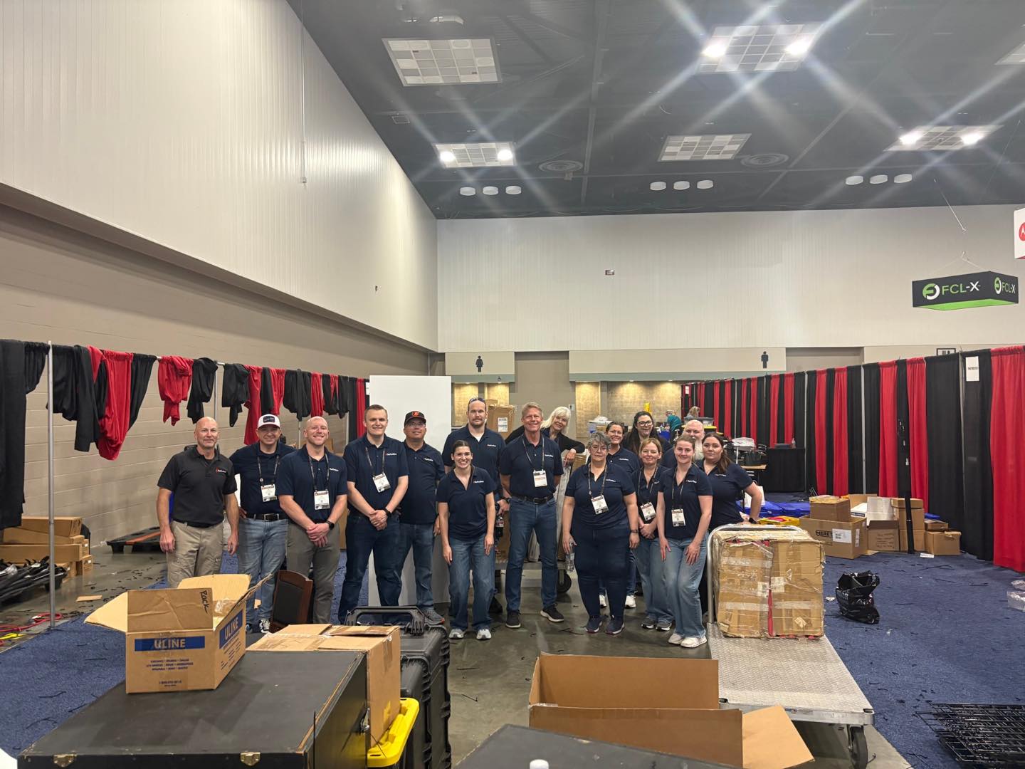 A group of people standing together in an indoor setting with boxes.