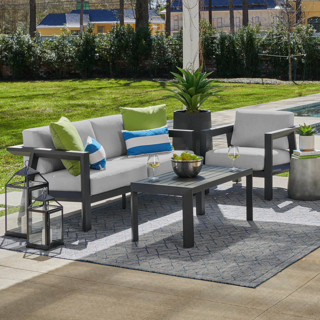 Outdoor seating area with a table, cushions, and potted plants.