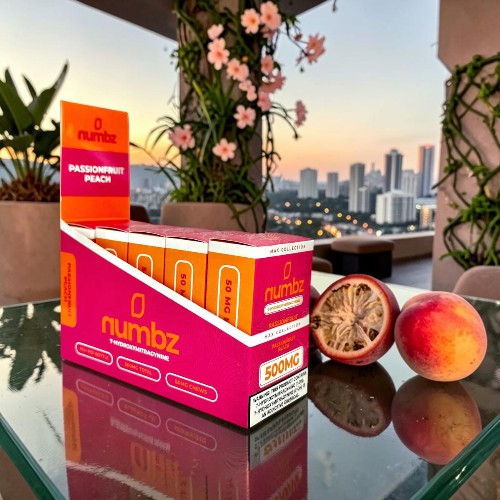 Box of numibz peach flavor with fruits and city skyline backdrop.