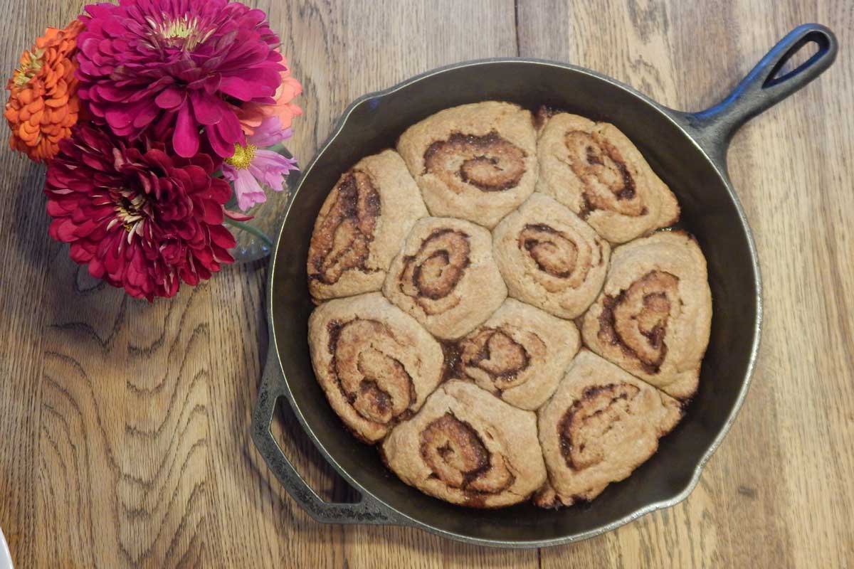 Final baked version of the cinnamon rolls in a cast iron skillet