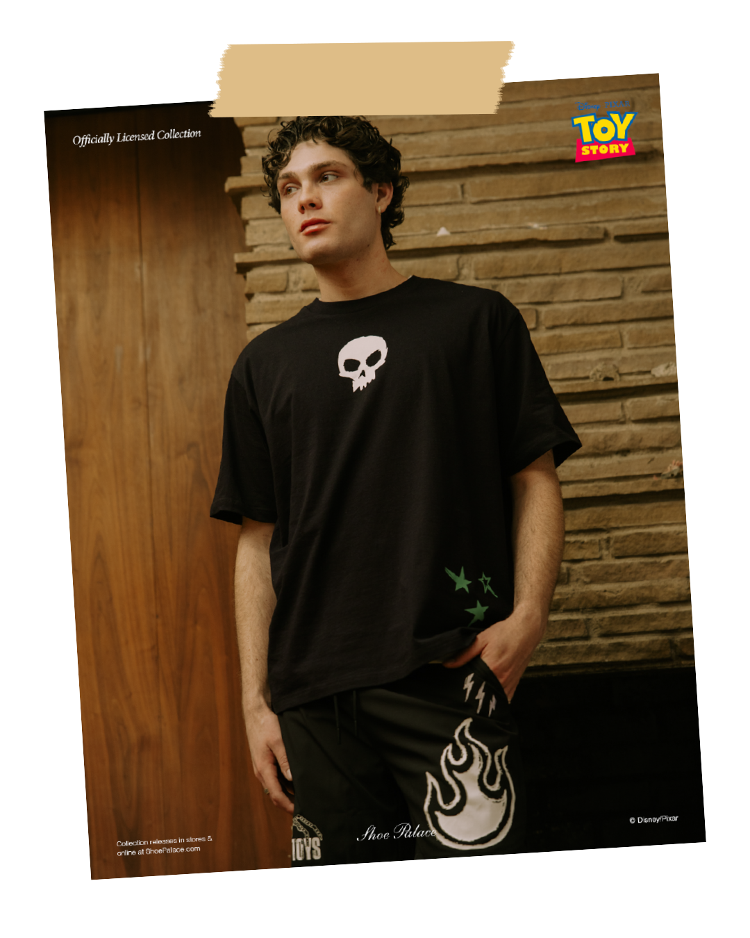 A person wearing a black t-shirt with a skull design and patterned shorts.