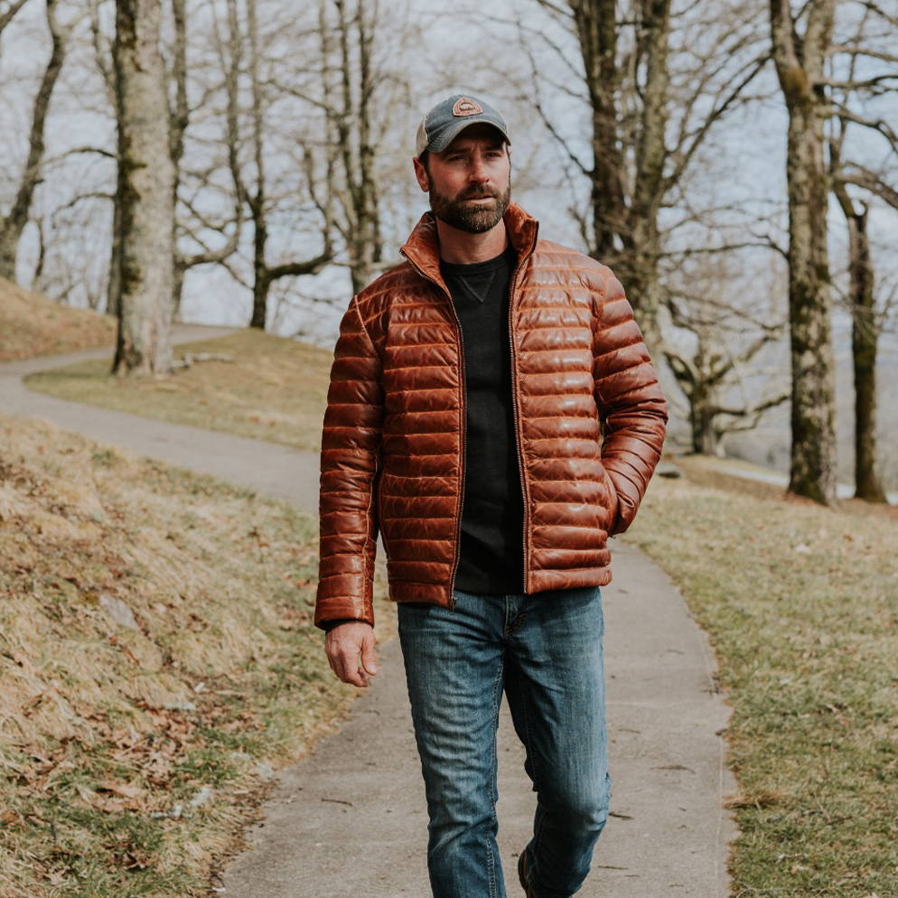 man walking on a trail in a leather jacketman standing with a motorcycle in a black leather jacket