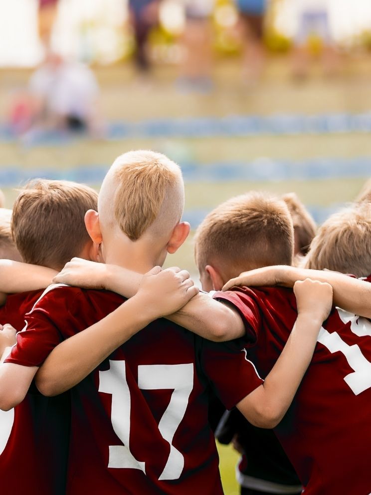Young boys sports team huddled together before the match in maroon uniforms with white letters