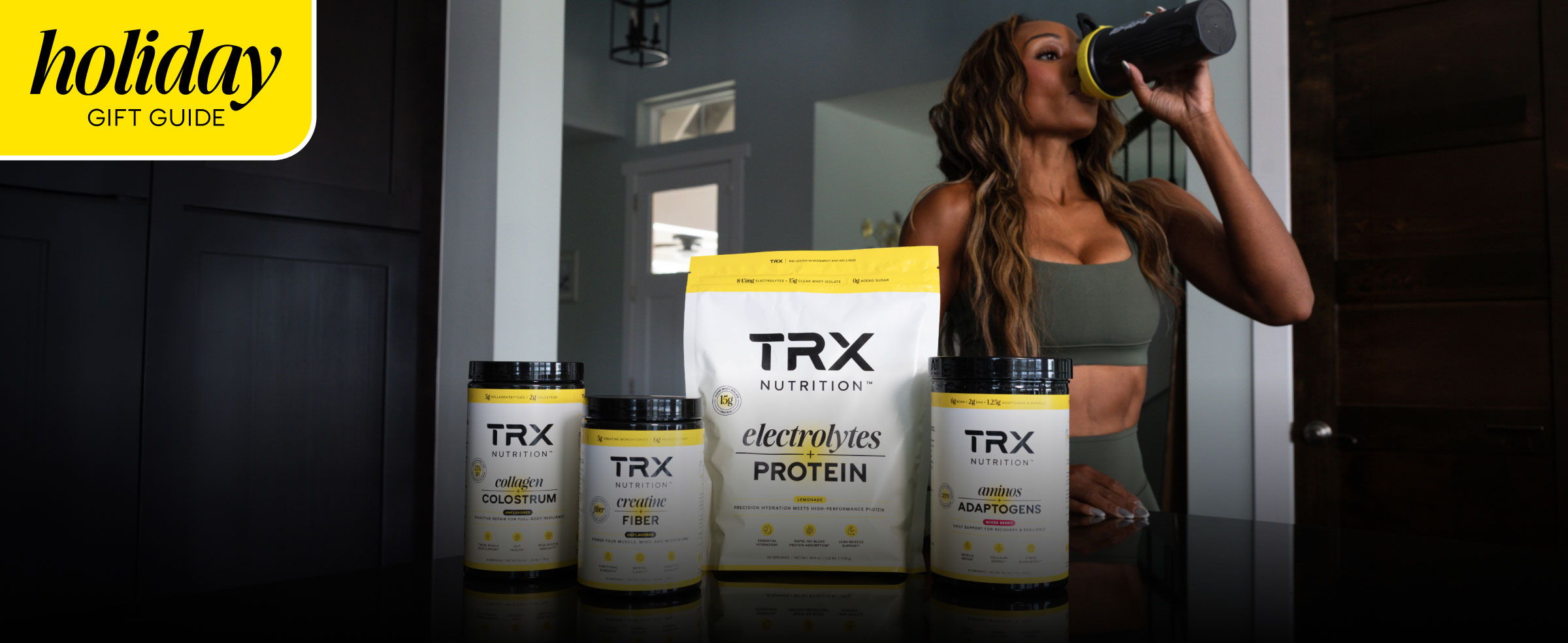 Woman drinking from a bottle, surrounded by fitness products.