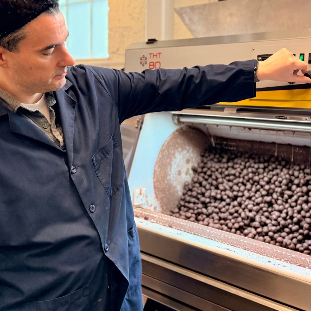 Person operating a machine with chocolate balls inside.