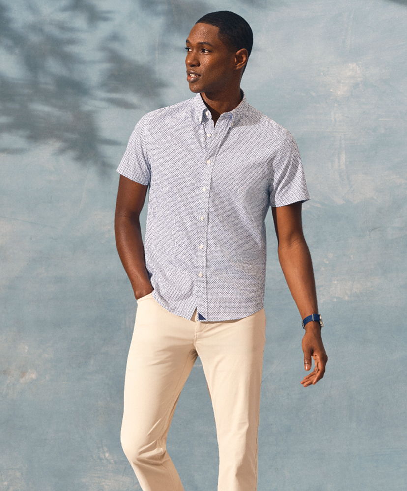 Man in casual shirt and pants against a blue background.