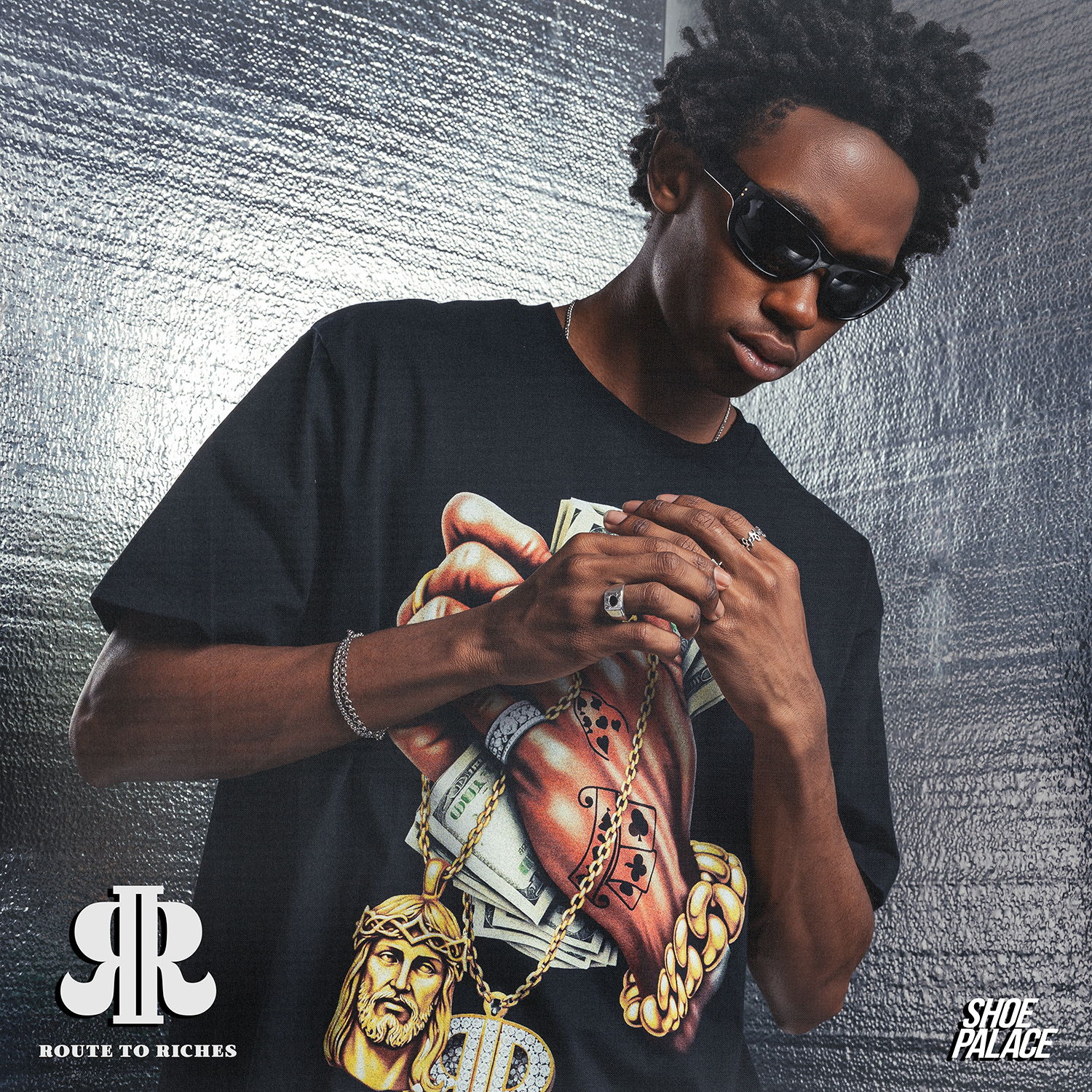 Person in a graphic t-shirt wearing sunglasses, posing against a textured background.