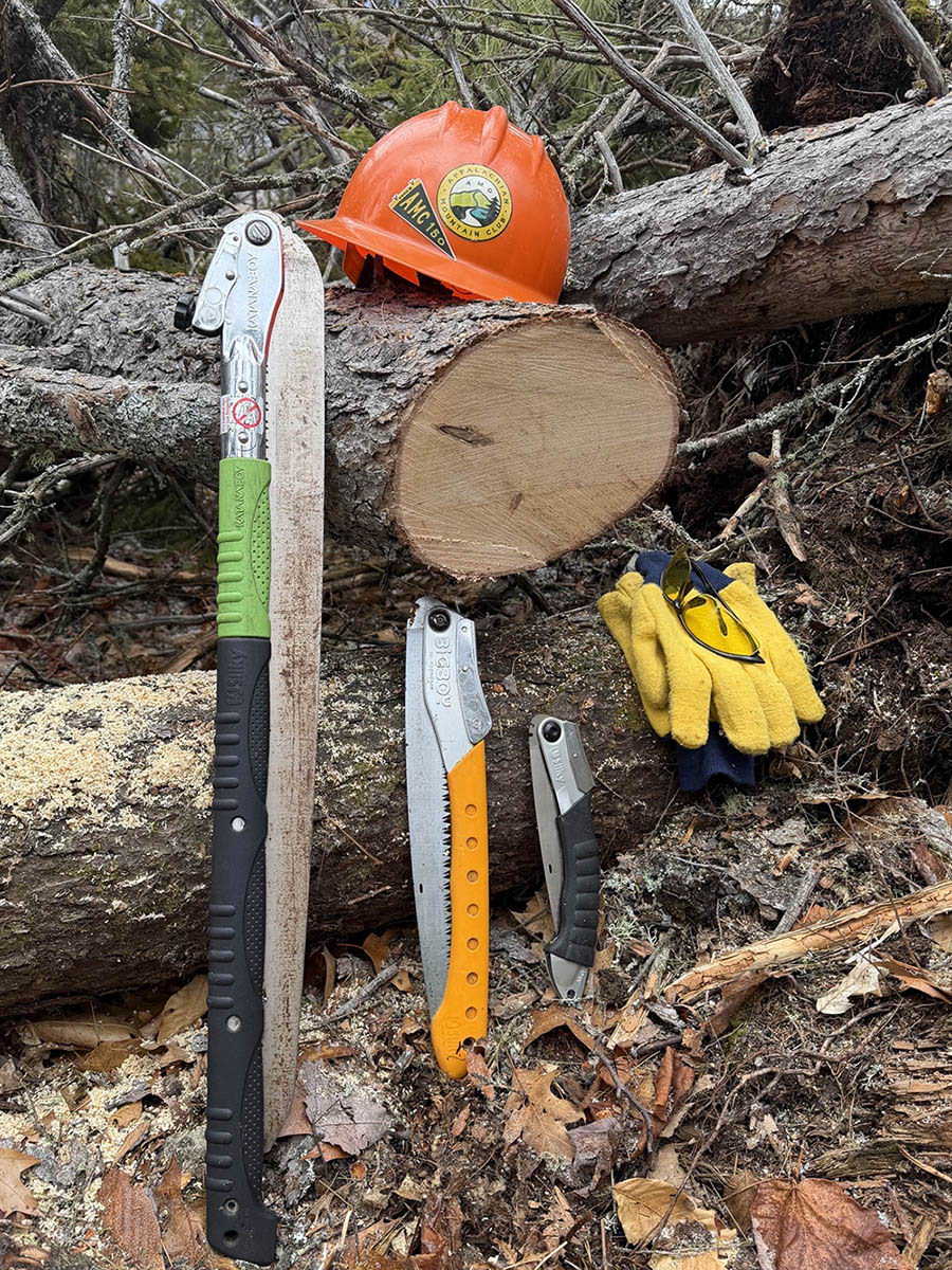Assorted tools and safety gear on a fallen tree trunk.