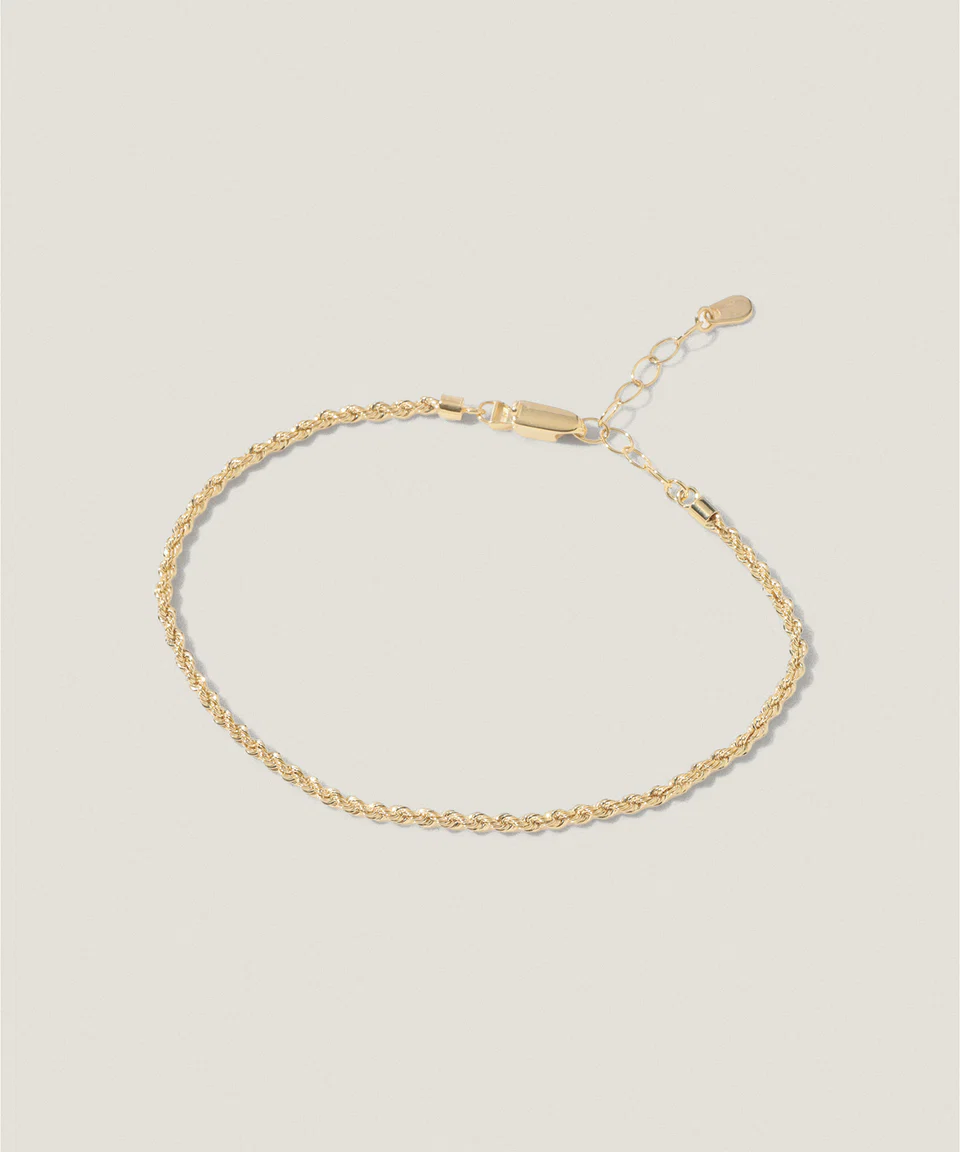 Gold chain bracelet on a light background.
