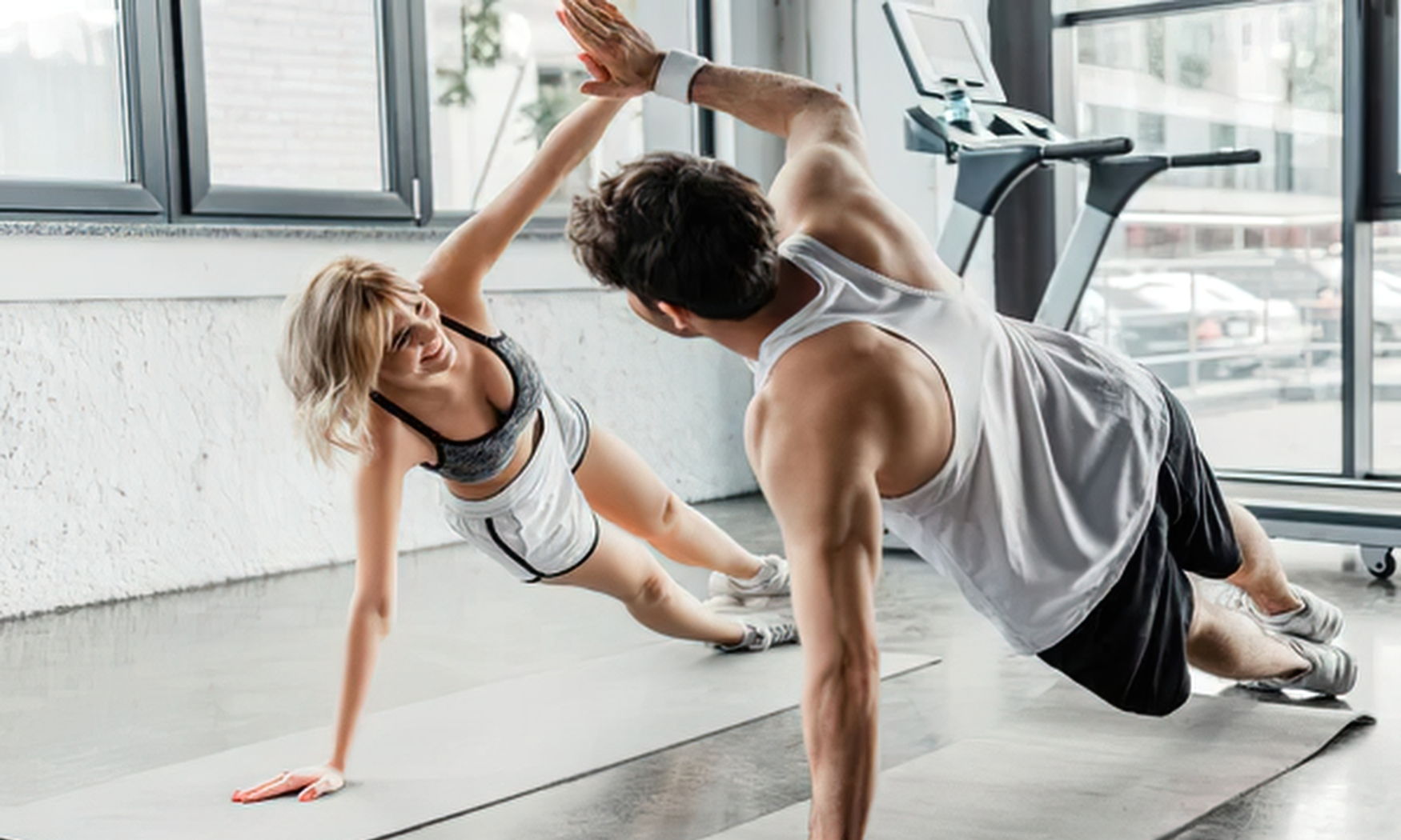 Two people doing push-ups and high-fiving in a gym.