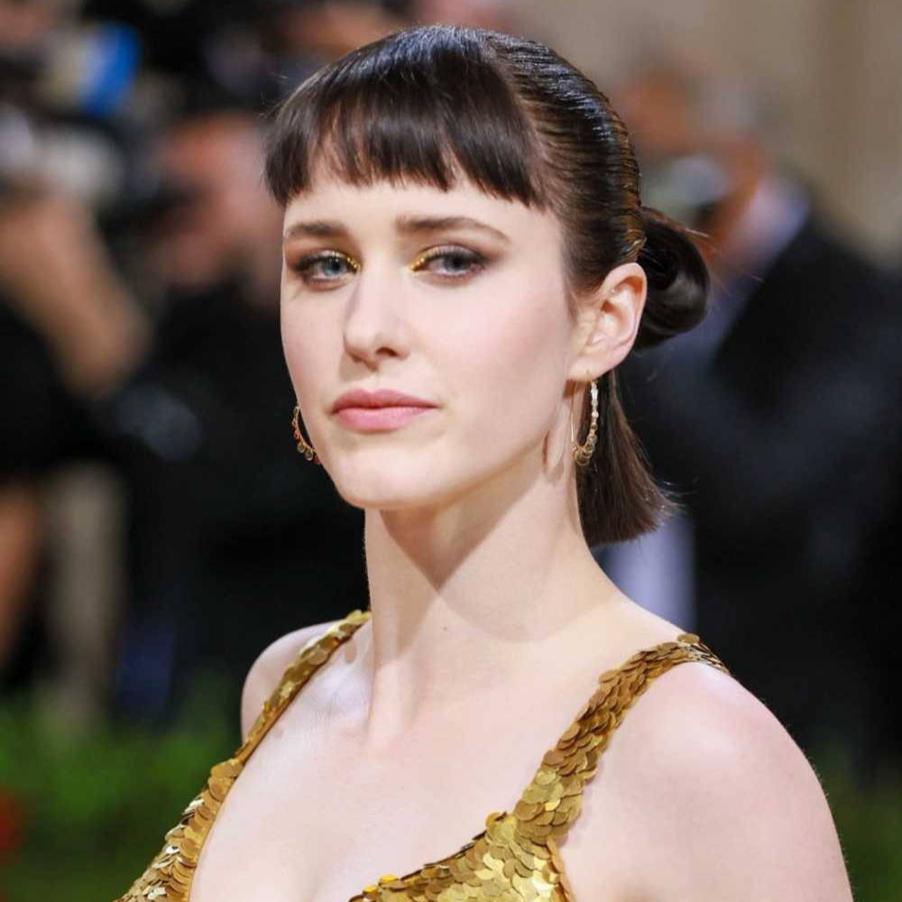 Person in a gold sequined outfit at a red carpet event.