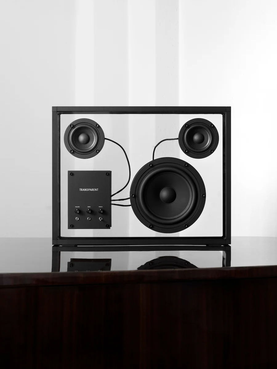 Black transparent speaker with two round woofers and control buttons.
