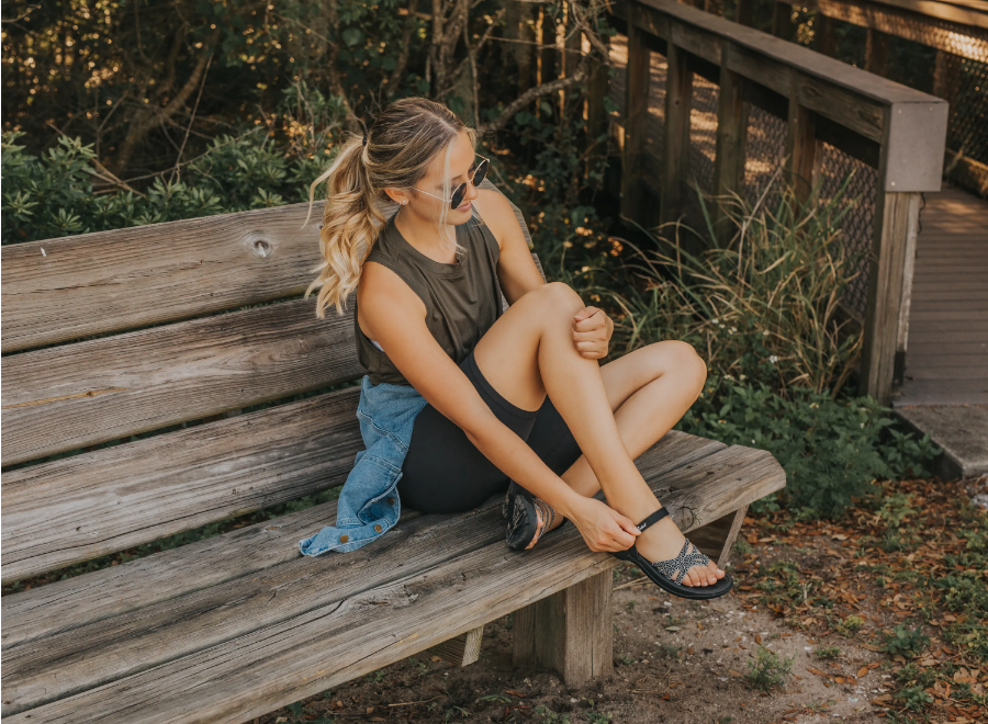 woman sitting on bench wearing sandals with arch support