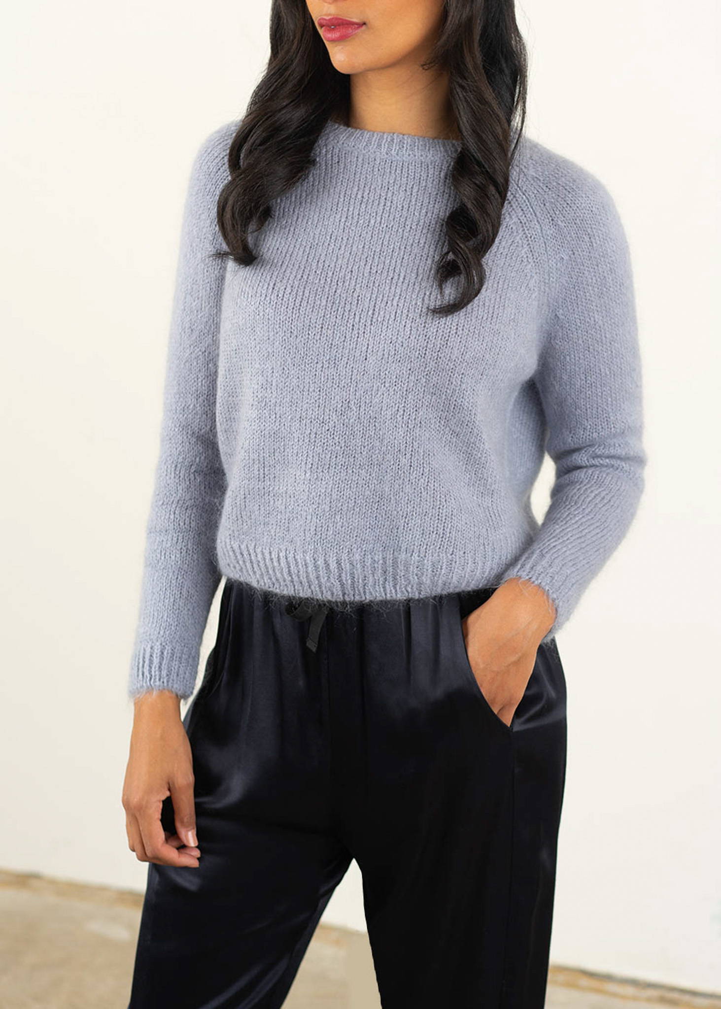 A model wearing a lilac knitted sweater over dark blue satin trousers