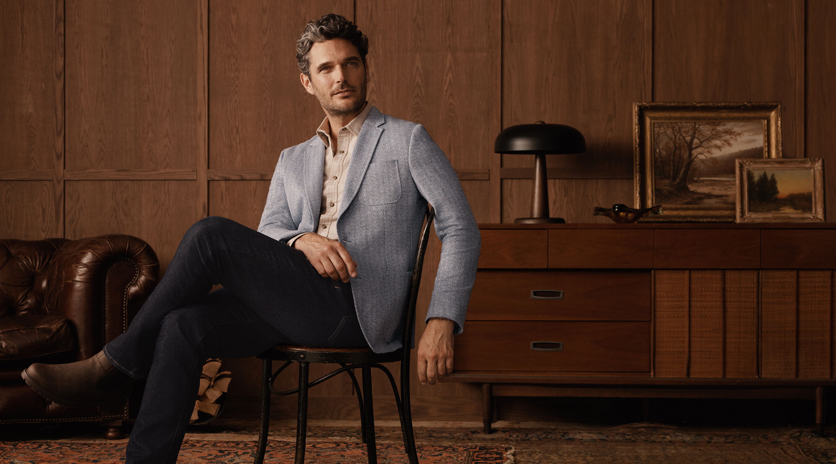 Man sitting on a chair in a stylish, vintage interior setting.