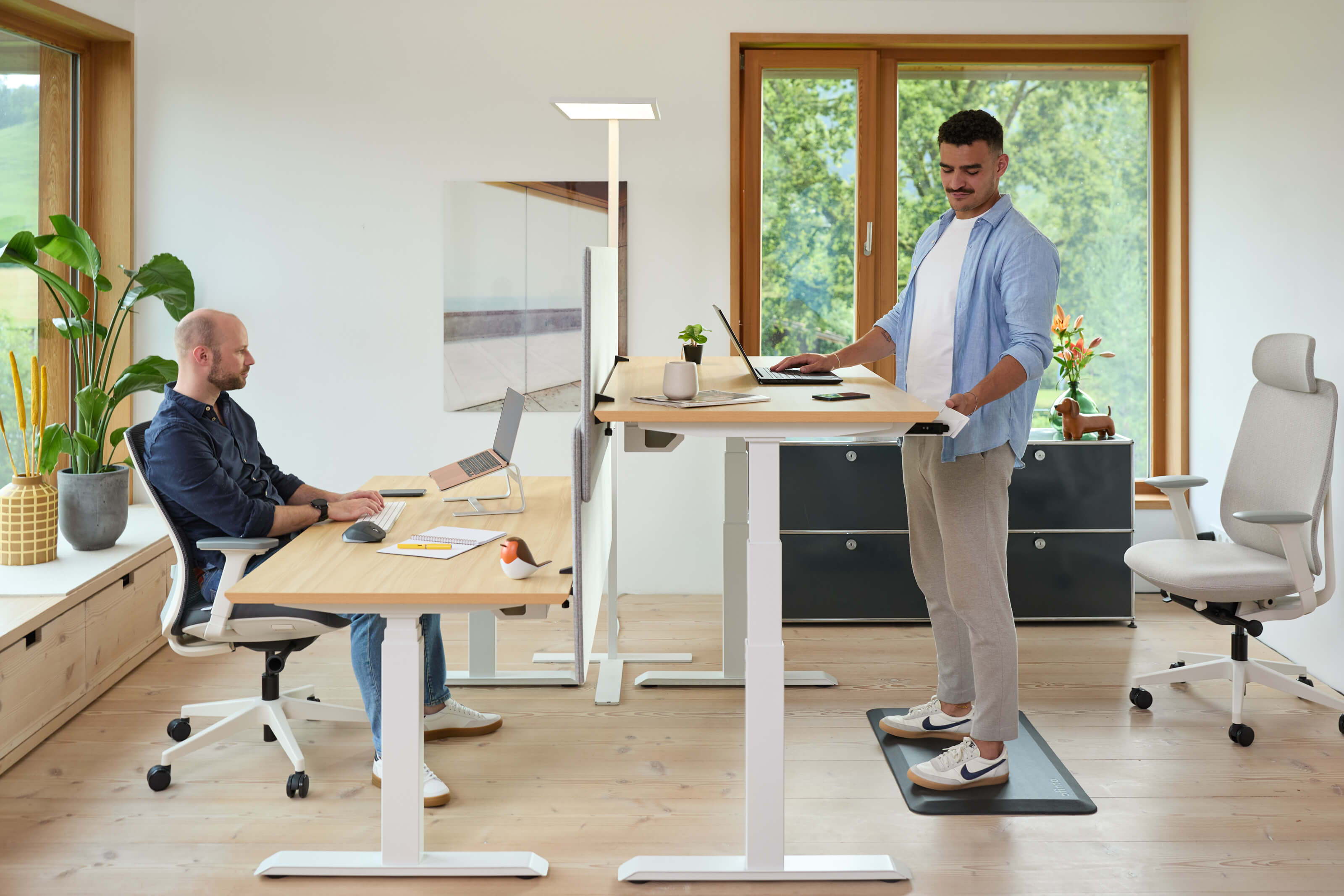 Zwei Männer in einem hellen, offenen Co-Working Space an zwei höhenverstellbaren Bürotischen Elevate von ofinto