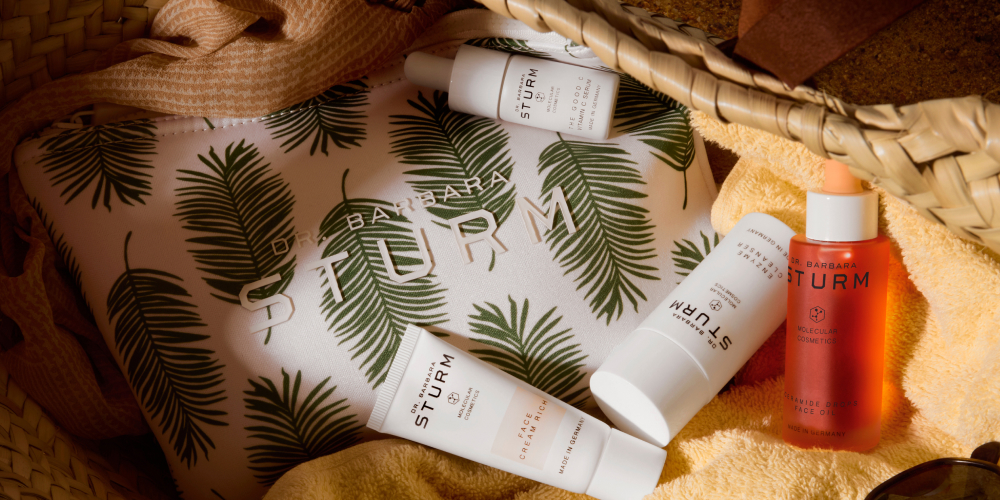 Skincare products arranged on a patterned background with tropical leaves.