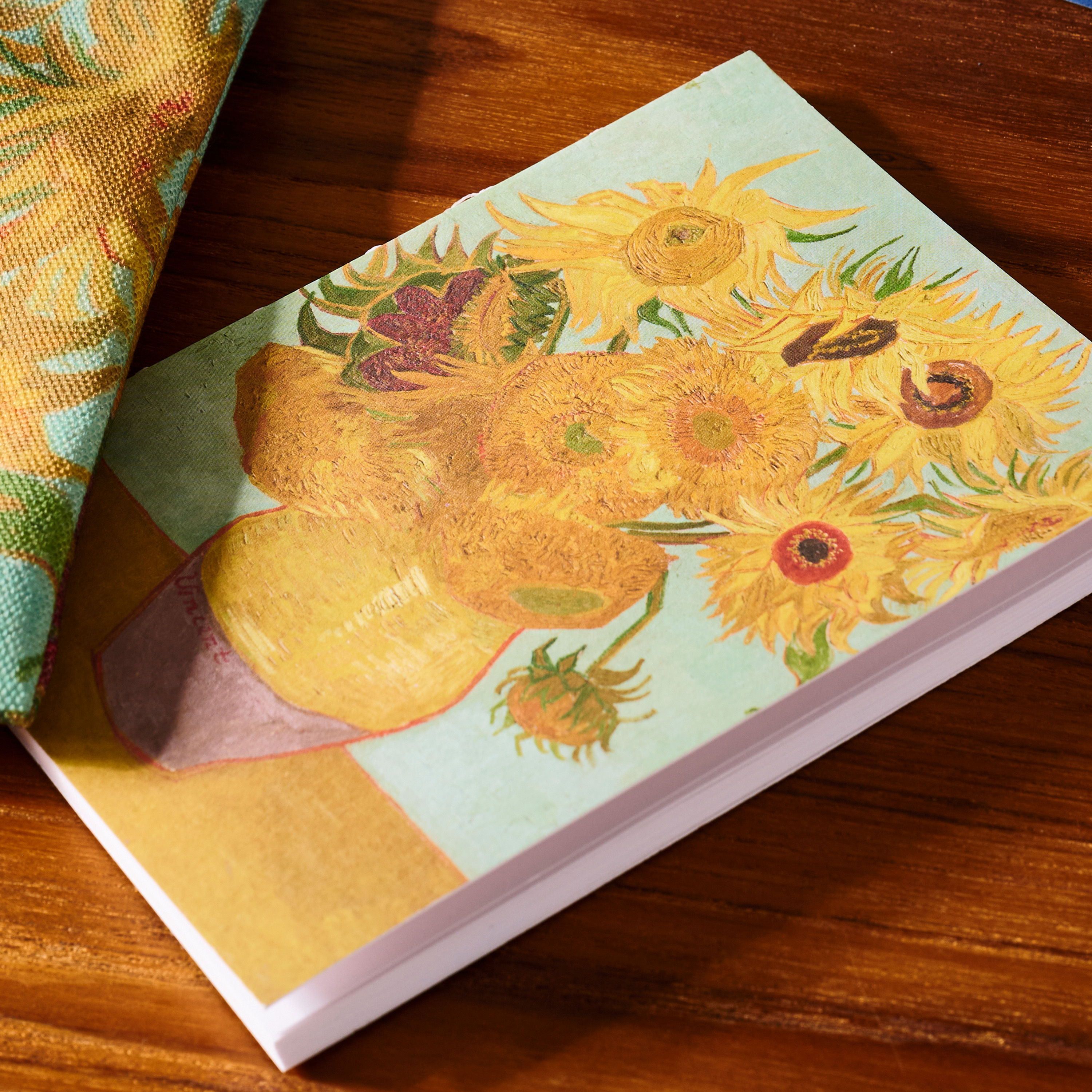Notebook featuring a painting of sunflowers on a wooden surface.