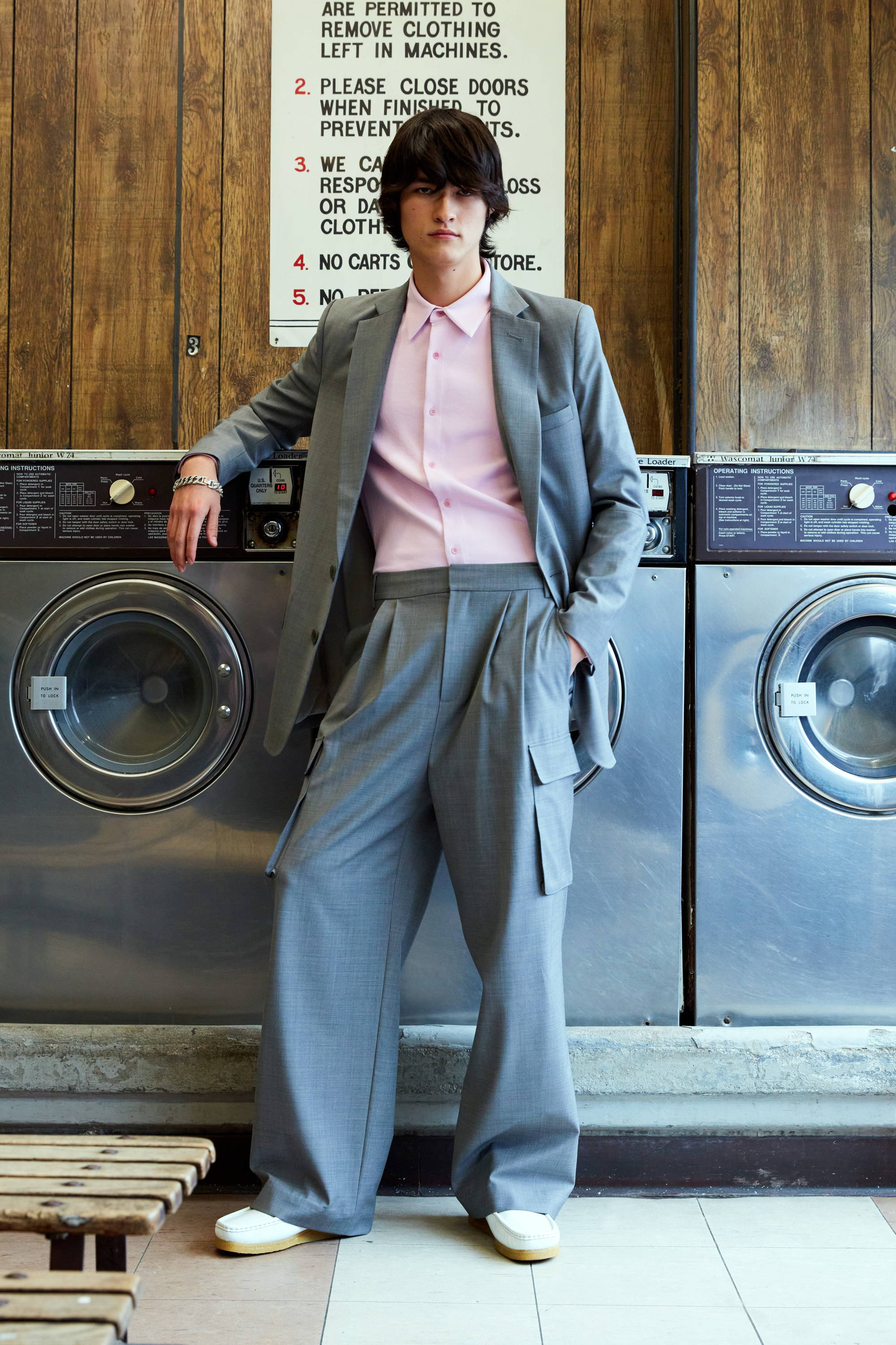 Person in a suit standing beside washing machines in a laundromat.