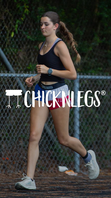A woman jogging on a track, wearing athletic clothing and shoes.